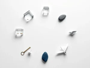 Zeven geometrische objecten in cirkelvorm op wit bureau: gouden sleutel, kristal, kompas, weegschaal, steen, origami kraanvogel, zandloper