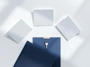 Zilveren huissleutel op blauwe map met vijf papieren kaarten in boog op wit bureau