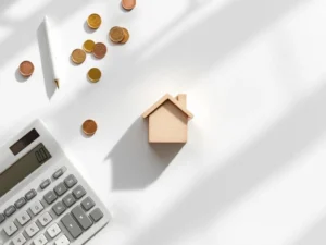 Rekenmachine, houten huisblok en euromuntjes op wit bureau voor hypotheekadvieskosten berekening